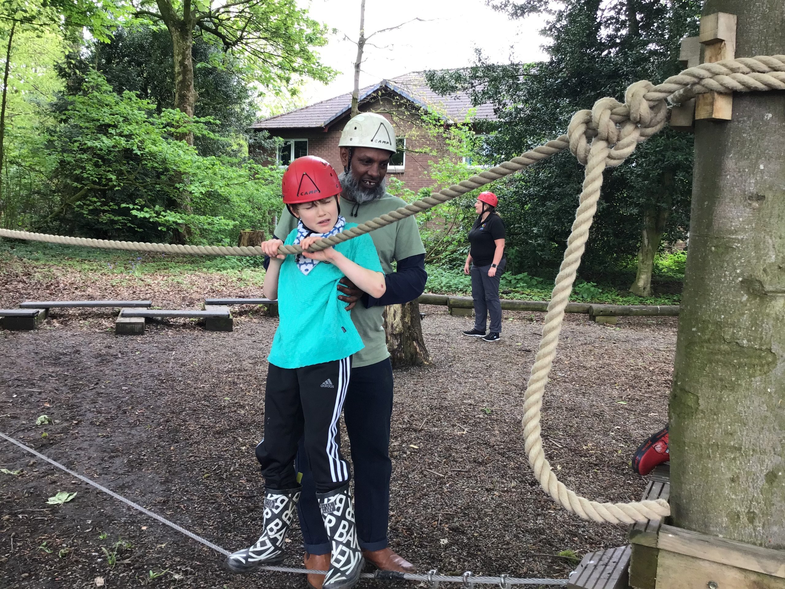 Student being supported by a staff member as they enjoy the obstacle course