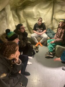 A group of students sit inside the cave challenge before they go in.