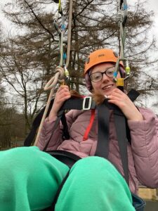 A student smiles as they enjoy being outside on the zip line.