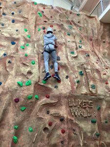 A student has almost climbed to the top of the climbing wall.