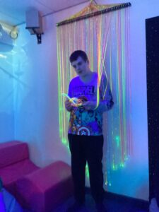 A student enjoys touching the fibre optic curtain and is engrossed with the sensory experience.