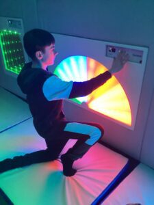 A rainbow of colours are visible as a student enjoys playing with the sensory equipment.