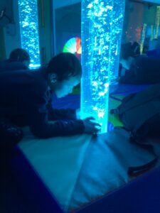 A student leans over and touches the colourful bubble tube with interest and fascination.