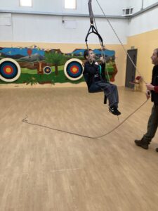 A student enjoys being swung around the sports hall in the accessible swing.