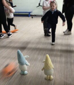A pupil enjoys their luck with kicking a ball at two soft gnomes.